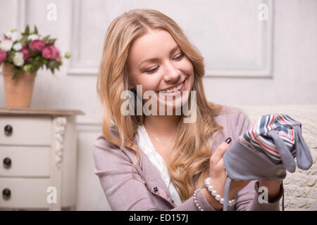 Giovane donna attraente holding baby hat , interior shot Foto Stock