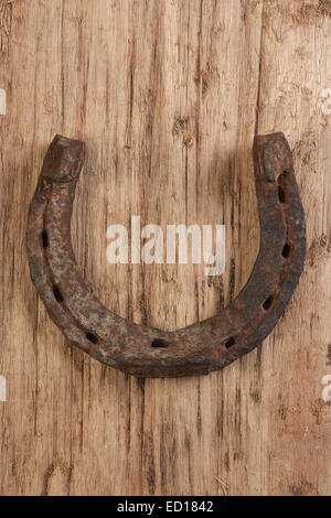 Vecchio arrugginito a ferro di cavallo su un sfondo di legno Foto Stock