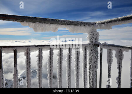 Paesaggio orizzontale di un gelo e neve balcone coperto in primo piano e uno spesso strato di nubi e alcune cime. Foto Stock