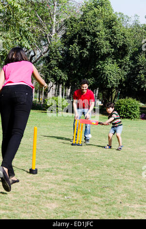 Indian genitori con parco per bambini a giocare a cricket Foto Stock