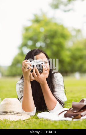 Sorridente brunette giacente su erba di scattare una foto Foto Stock