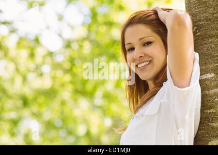 Ritratto di un grazioso redhead sorridente contro il tronco Foto Stock