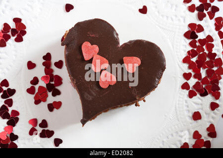 A forma di cuore di cioccolato tripla cielo dessert con spruzzata cuori su bianco centrino - ideale per il giorno di San Valentino, il giorno di San Valentino Foto Stock