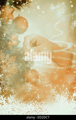 Immagine composita della donna Appendere le decorazioni di Natale su albero Foto Stock