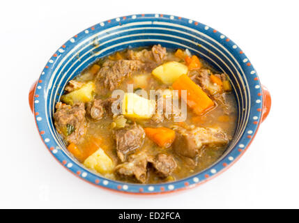 Stufato di manzo con carne, le patate e le carote in un piatto di ceramica isolata su bianco. Foto Stock