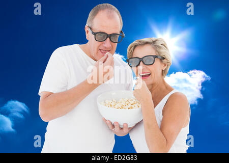 Immagine composita della coppia matura indossando occhiali 3d mangiare popcorn Foto Stock