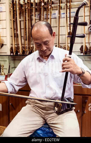 La musica il proprietario del negozio a Shanghai in Cina svolge Erhu fiddle cinese Foto Stock