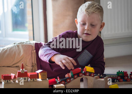 Ragazzo giocando con treni di legno insieme Foto Stock