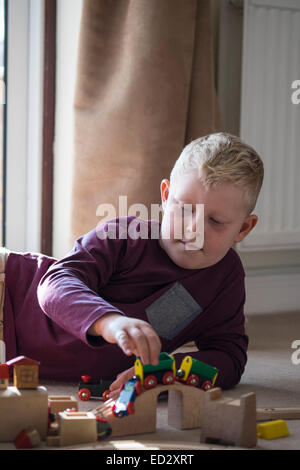 Ragazzo giocando con treni di legno insieme Foto Stock