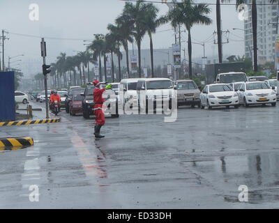 Manila, Filippine. 24 dicembre, 2014. Un traffico enforcer vestito di Santa Claus vestito portato alcuni festosa allegria per le strade di Pasay City come ha diretto le vetture in una piovosa vigilia di Natale. Credito: Sherbien Dacalanio/Pacific Press/Alamy Live News Foto Stock