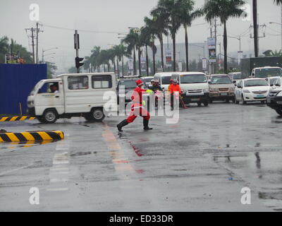 Manila, Filippine. 24 dicembre, 2014. Un traffico enforcer vestito di Santa Claus vestito portato alcuni festosa allegria per le strade di Pasay City come ha diretto le vetture in una piovosa vigilia di Natale. Credito: Sherbien Dacalanio/Pacific Press/Alamy Live News Foto Stock