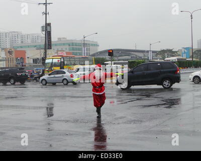 Manila, Filippine. 24 dicembre, 2014. Un traffico enforcer vestito di Santa Claus vestito portato alcuni festosa allegria per le strade di Pasay City come ha diretto le vetture in una piovosa vigilia di Natale. Credito: Sherbien Dacalanio/Pacific Press/Alamy Live News Foto Stock