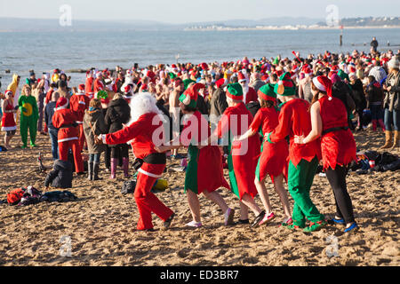 Boscombe, Bournemouth, Dorset UK. 25 Dic 2014. Giorno di Natale 25 dicembre 2014. Tuffo bianco di Natale a Boscombe, Bournemouth, Dorset, Regno Unito. Coraggiosi volontari si tuffano nel freddo del mare per la settima nuotata annuale di Natale mattina di beneficenza, vestiti in costumi di fantasia e raccogliendo soldi per Macmillan cura locale a Christchurch, un'unità di cura palliativa specializzata per i pazienti nella comunità locale. Centinaia di persone hanno preso parte all'evento, che è diventato una tradizione popolare per molti prima del pranzo. Credit: Carolyn Jenkins/Alamy Live News Foto Stock