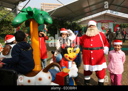 Santa Claus pone con i bambini del Bangladesh per fotografie durante una festa di Natale a Dhaka il 25 dicembre 2014. Foto Stock