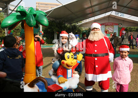 Santa Claus pone con i bambini del Bangladesh per fotografie durante una festa di Natale a Dhaka il 25 dicembre 2014. Foto Stock