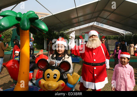 Santa Claus pone con i bambini del Bangladesh per fotografie durante una festa di Natale a Dhaka il 25 dicembre 2014. Foto Stock