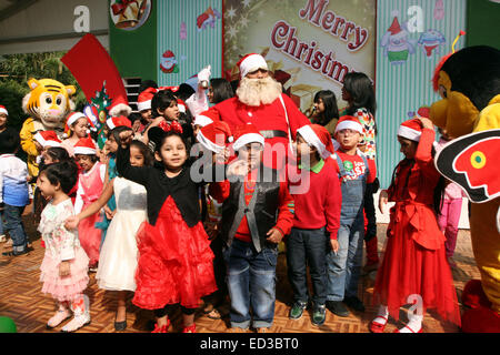 Santa Claus pone con i bambini del Bangladesh per fotografie durante una festa di Natale a Dhaka il 25 dicembre 2014. Foto Stock