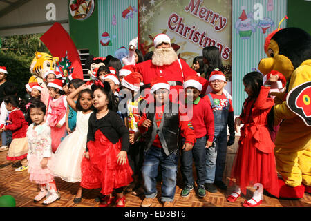 Santa Claus pone con i bambini del Bangladesh per fotografie durante una festa di Natale a Dhaka il 25 dicembre 2014. Foto Stock