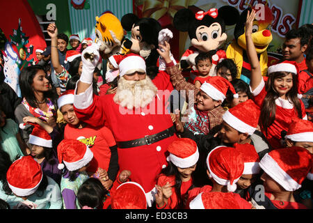 Santa Claus pone con i bambini del Bangladesh per fotografie durante una festa di Natale a Dhaka il 25 dicembre 2014. Foto Stock