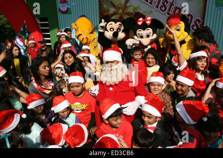 Santa Claus pone con i bambini del Bangladesh per fotografie durante una festa di Natale a Dhaka il 25 dicembre 2014. Foto Stock