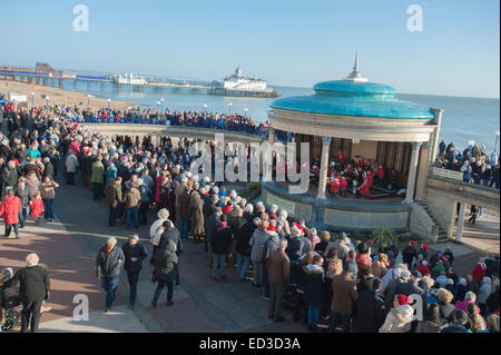 Eastbourne Pier, Sussex, Regno Unito . 25 dic 2014. Le persone si sono riunite per ascoltare musica tradizionale al palco per spettacoli. Mostra anche il molo che è in fase di riparazione dopo un incendio di grandi dimensioni nella prima parte dell'anno 2014 Foto Stock