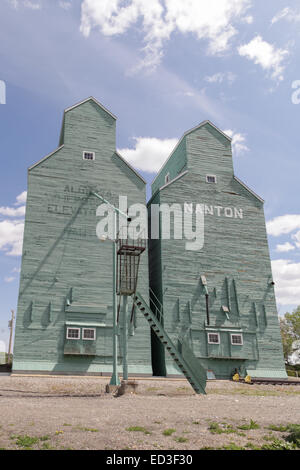 Nanton, Alberta, silos per il grano di elevatori a fianco del binario luminosamente in disuso di legno verniciato Foto Stock