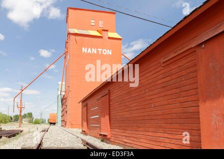 Nanton, Alberta, silos per il grano di elevatori a fianco del binario luminosamente in disuso di legno verniciato Foto Stock