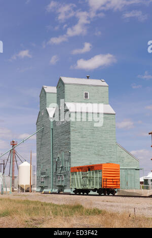 Nanton, Alberta, silos per il grano di elevatori a fianco del binario luminosamente in disuso di legno verniciato Foto Stock