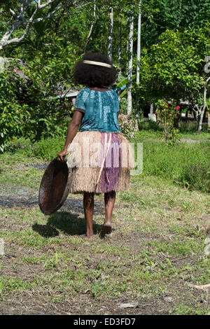 La Melanesia, Papua Nuova Guinea, Dobu isola. Donna in erba gonna con piastra in legno. Foto Stock