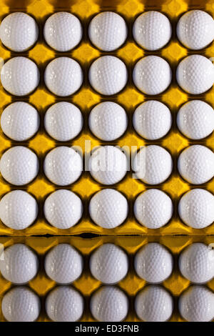 Palline da golf nel foglio di carta cartone per le uova su una scrivania in vetro Foto Stock