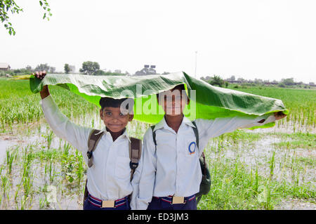 2 rurale indiano bambini ragazzi studenti in possesso della foglia la stagione delle pioggie da gustare Foto Stock