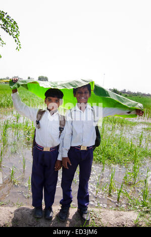 2 rurale indiano bambini ragazzi studenti in possesso della foglia la stagione delle pioggie da gustare Foto Stock