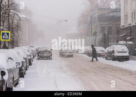 Mosca, Russia. 25 dicembre, 2014. Meteo: Heavy snowstorm oggi a Mosca. Freddo e ventoso giorno, bassa temperatura fino a -8C (-22F) e neve pesante. La prima tempesta di neve nella stagione dopo un mese di caligine e sporcizia. Stagione invernale infine arrivò al potere alla vigilia del nuovo anno e del Natale ortodosso vacanze. Coperta di neve della strada di Mosca. Unidentified, irriconoscibile pedone attraversa la strada. Credito: Alex Immagini/Alamy Live News Foto Stock