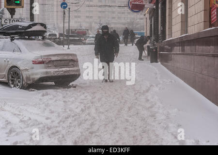 Mosca, Russia. 25 dicembre, 2014. Meteo: Heavy snowstorm oggi a Mosca. Freddo e ventoso giorno, bassa temperatura fino a -8C (-22F) e neve pesante. La prima tempesta di neve nella stagione dopo un mese di caligine e sporcizia. Stagione invernale infine arrivò al potere alla vigilia del nuovo anno e del Natale ortodosso vacanze. Ventoso e nevoso giorno. Irriconoscibile, non identificato pedoni andare giù per la strada. Credito: Alex Immagini/Alamy Live News Foto Stock