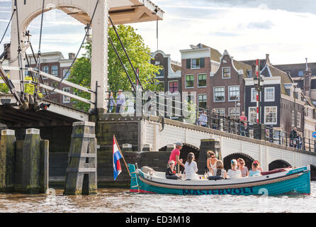 Amsterdam Amstel River con skinny ponte Magere Brug con elettrico noleggio barca con le ragazze giovani donne partying, bere vino. Foto Stock