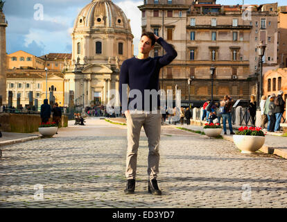 Attraente giovane uomo a Roma in piedi di fronte a Santa Maria di Loreto la Chiesa, guardando lontano Foto Stock