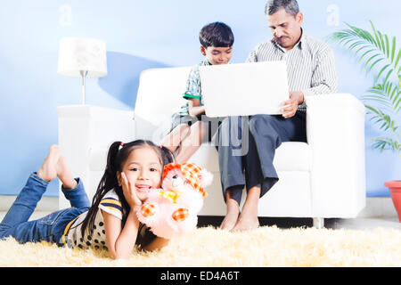 Padre indiano con i bambini a guardare per laptop Foto Stock