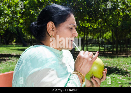 Indian vecchia donna park godere di bere il cocco Foto Stock