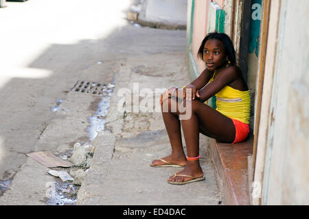 Giovane ragazza seduta su una porta di casa a Cuba Foto Stock