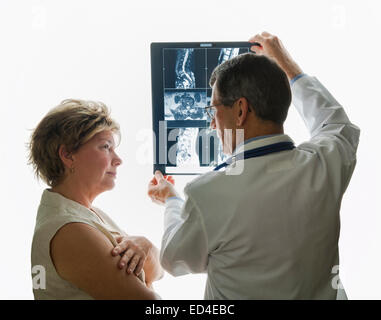 Medico maschio e femmina matura visualizzazione paziente e discutere di MRI spinale o a raggi X, scansioni. Foto Stock