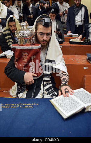 Adoratore tenendo un piccolo Torah durante i giorni feriali le preghiere del mattino a Lubavitch sede a Brooklyn, New York Foto Stock