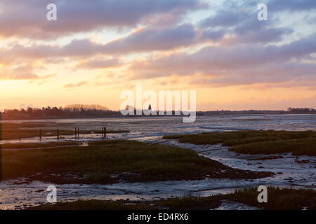 Chichester Harbour Sunrise. Alba colorata che si infrangono sul villaggio di Bosham con bassa marea. Bagliore sulle paludi e sul fango che circondano la zona. Foto Stock