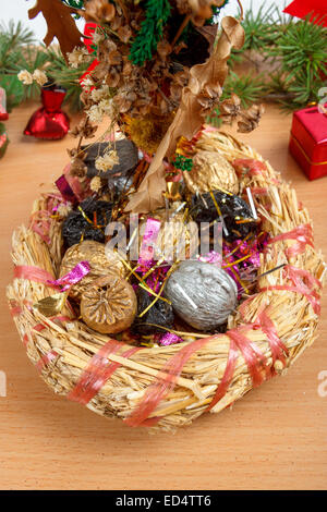 Meravigliosa decorazione natalizia con cesto in vimini con paglia e dadi colorati all'interno in legno marrone chiaro superficie. Christian fe Foto Stock