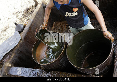 Esclusiva - BOJONEGORO, Indonesia. 13 novembre 2014 - Un lavoratore raccoglie di olio grezzo per essere trasformati in combustibile nel sottodistretto Ke Foto Stock