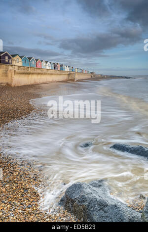 La luce del mattino sulla pittoresca spiaggia di capanne sul lungomare southwold. Prese con onde sulla spiaggia a marea alta. Foto Stock