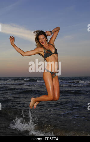 La donna a swim-suit salto sulla spiaggia Foto Stock