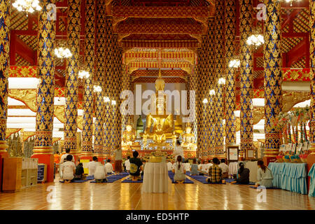 Statua di Buddha e adoratori, sala da preghiera, Wat Suan Dok, Chiang Mai, Thailandia Foto Stock