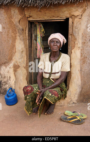 Anziani Non vedenti donna seduta al di fuori del suo con tetto di paglia di capanna di fango, Gambaga, Ghana Foto Stock