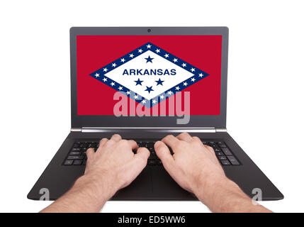 Mani lavorando su laptop che mostra sullo schermo la bandiera di Arkansas Foto Stock