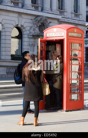 I turisti cinesi prendendo fotografie della ragazza in un telefono rosso Box London Inghilterra England Foto Stock